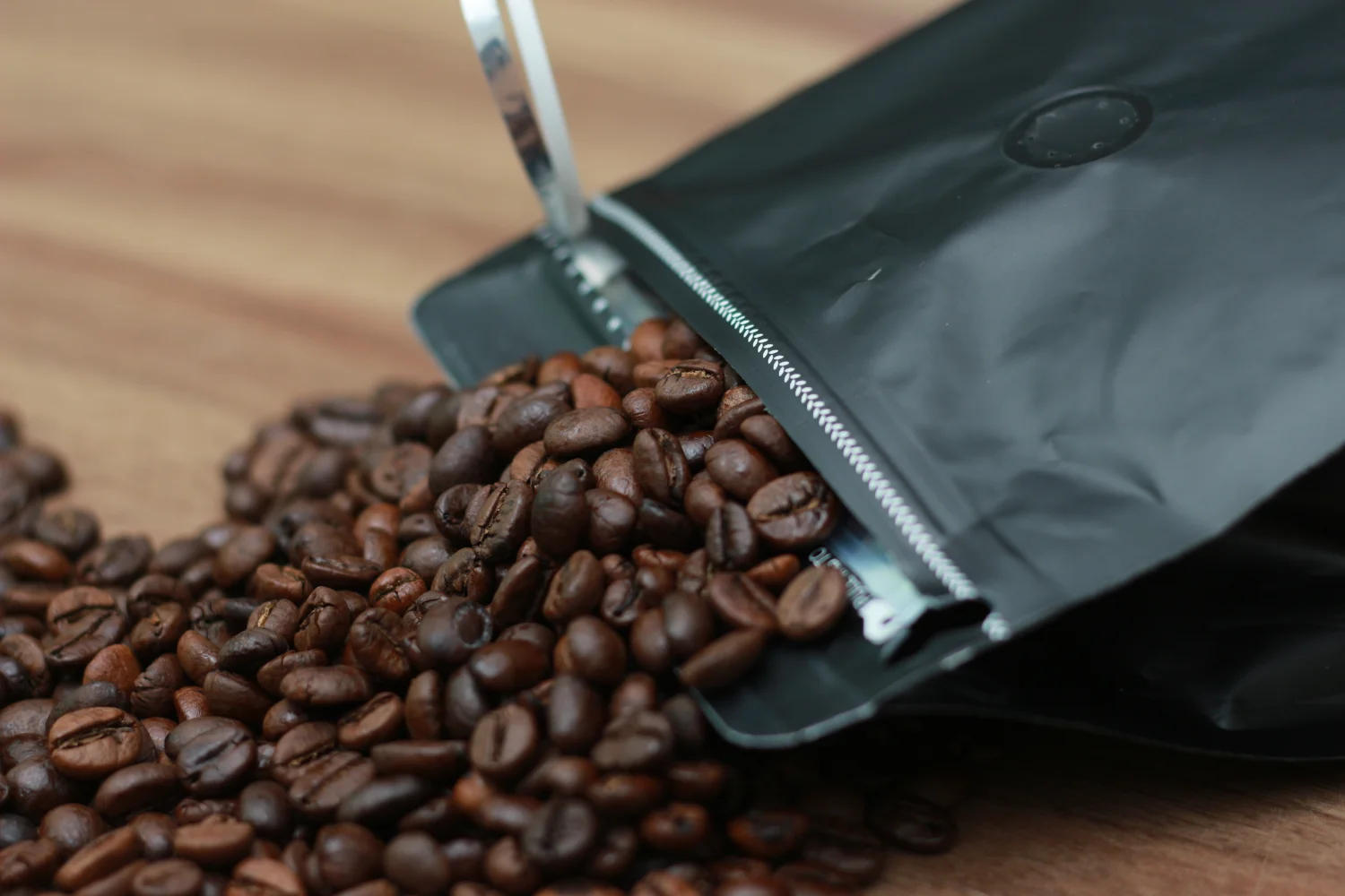One-way degassing valve on black coffee flexible packaging bag — allows CO₂ to escape after roasting while preventing oxygen ingress to preserve coffee freshness