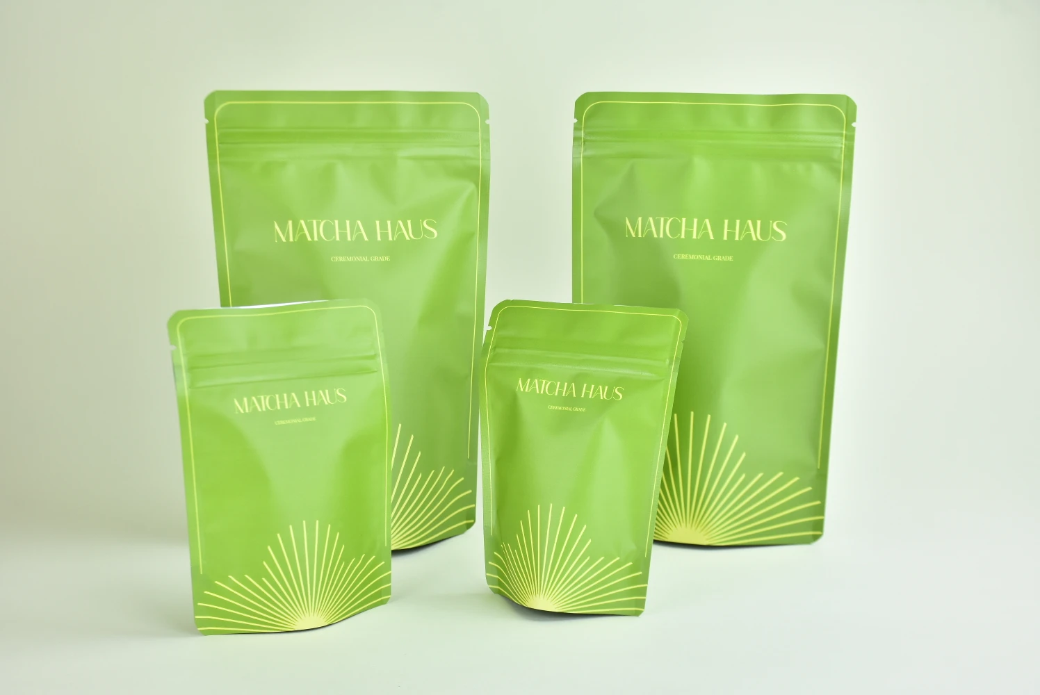 Custom printed stand-up pouches in four sizes produced by JINYI factory — matte green finish with gold hot stamping for Matcha Haus ceremonial grade tea brand