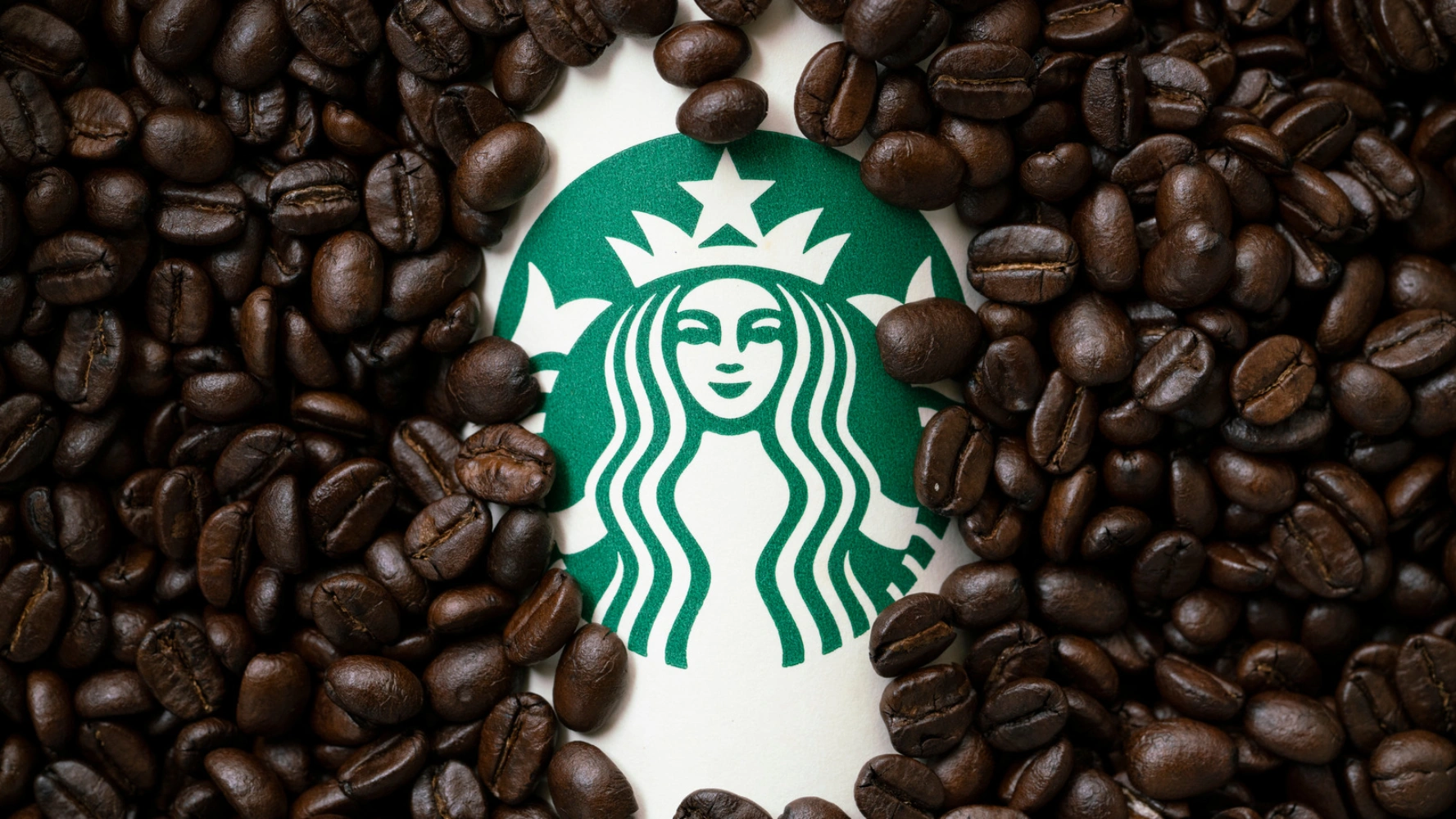 Starbucks brand logo on roasted coffee beans background — global coffee packaging reference