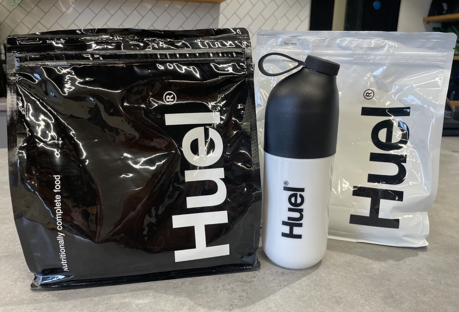 Huel Black Edition large-format stand-up pouch with shaker bottle — black high-protein meal replacement powder packaging showing foil-lined flexible bag design