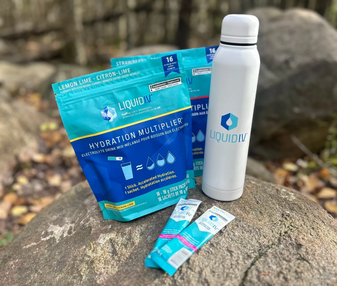 Liquid IV hydration multiplier resealable stand-up pouch and stick packs in outdoor lifestyle setting — electrolyte drink mix packaging designed for active and travel use cases