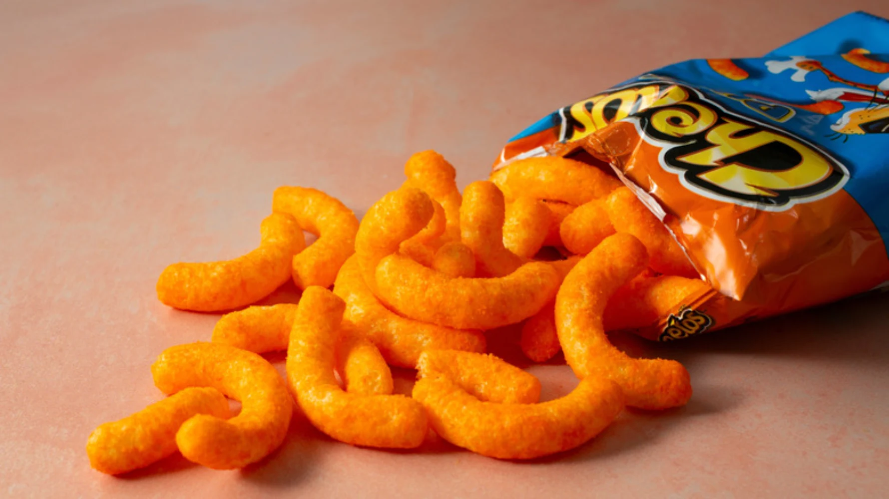 Cheetos crunchy cheese puffs spilling out of an open orange bag on a surface