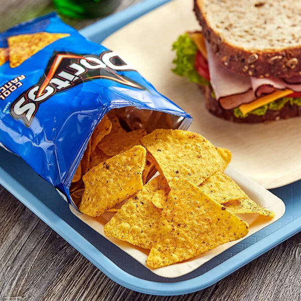 Open Doritos Nacho Cheese bag with tortilla chips spilling out next to a sandwich