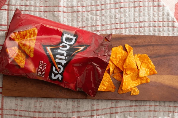 Doritos Nacho Cheese pillow bag packaging with chips on a wooden surface