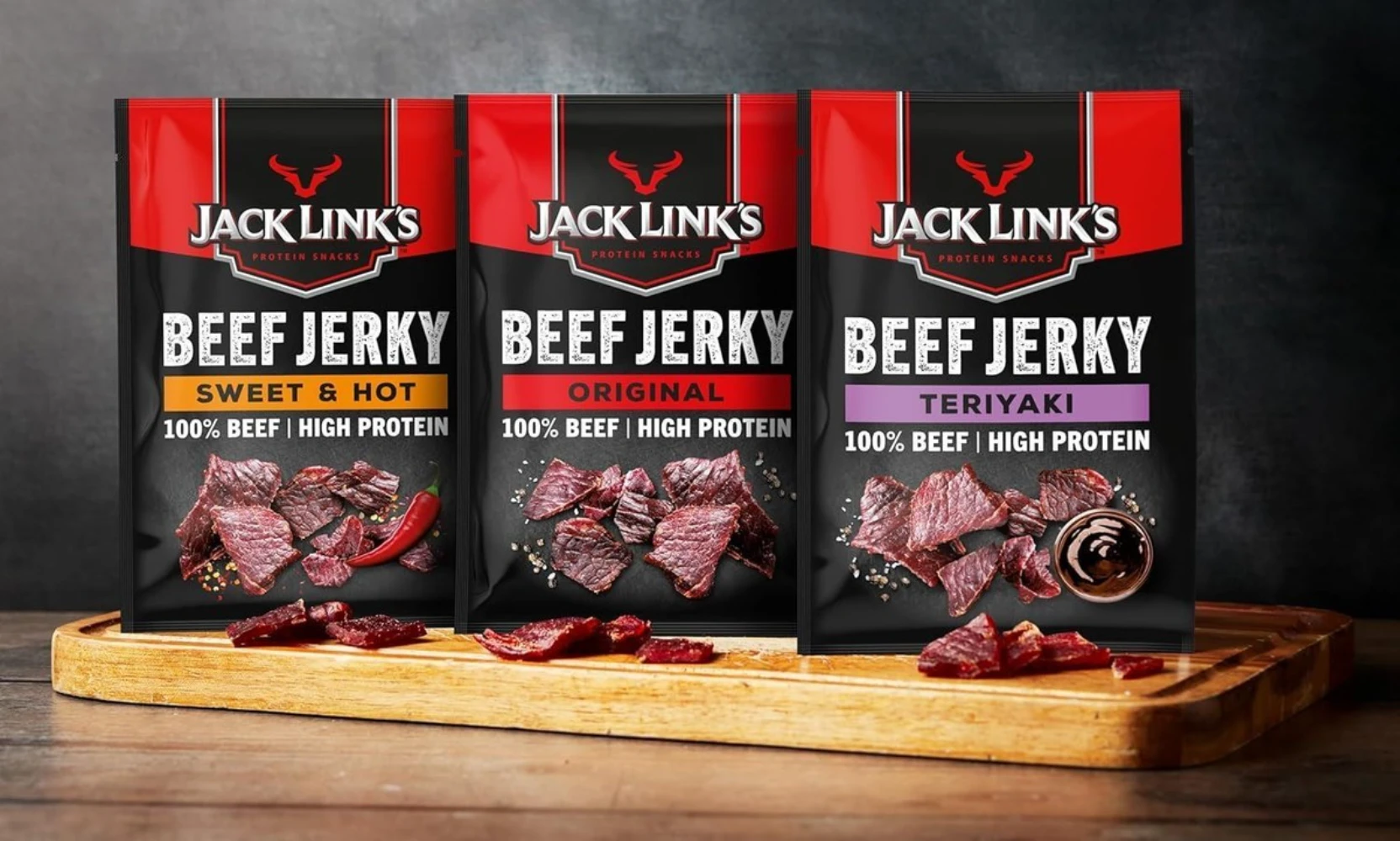 Jack Link's beef jerky stand-up pouches in sweet hot and teriyaki flavors displayed on a wooden board