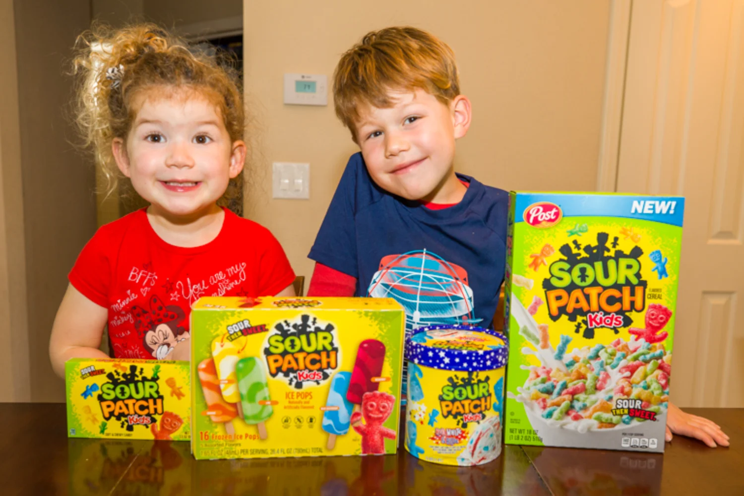 Two children posing with Sour Patch Kids candy bags and cereal box product range