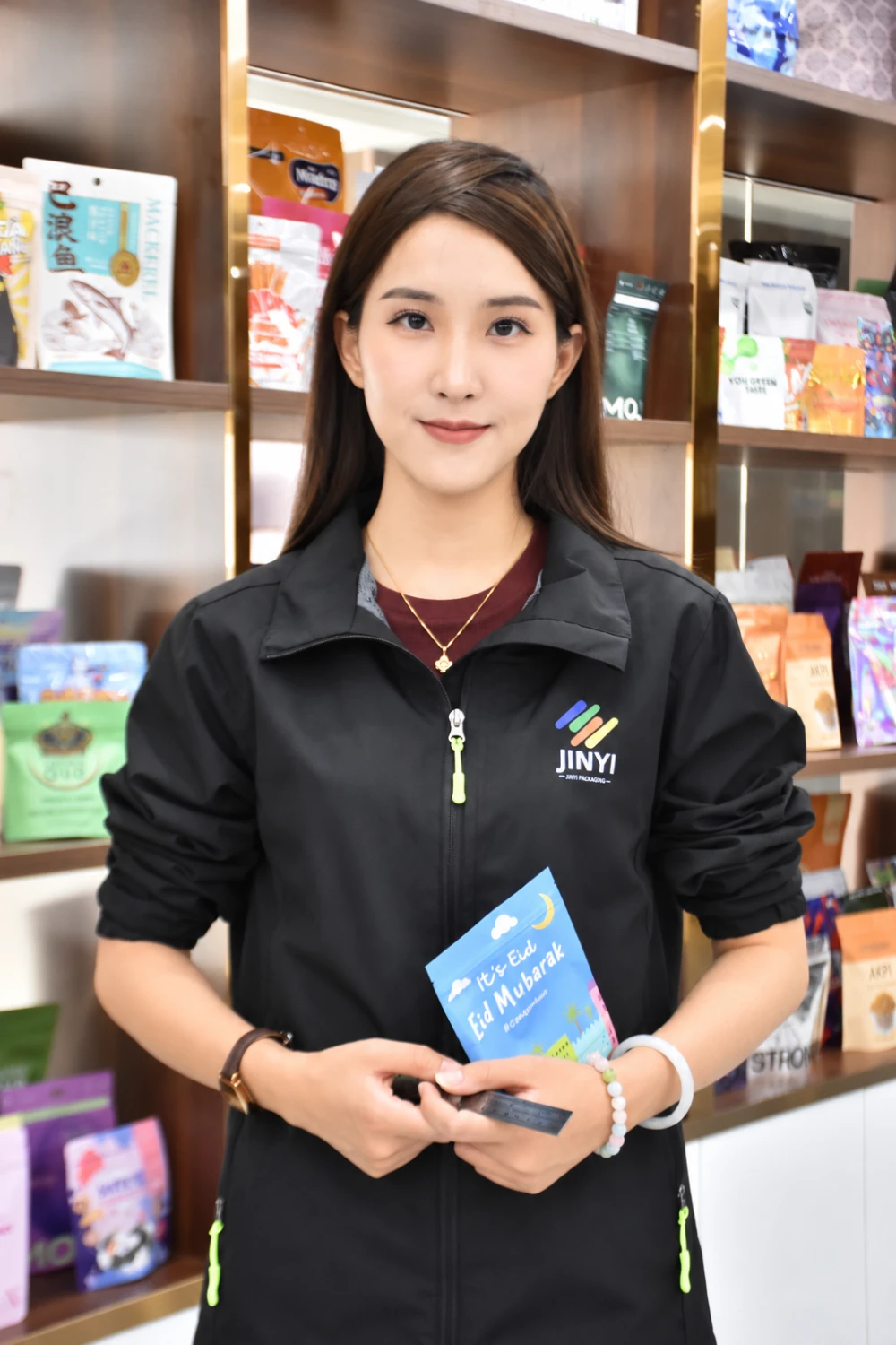 Elsa holding a pouch sample and ruler in the JINYI Packaging showroom